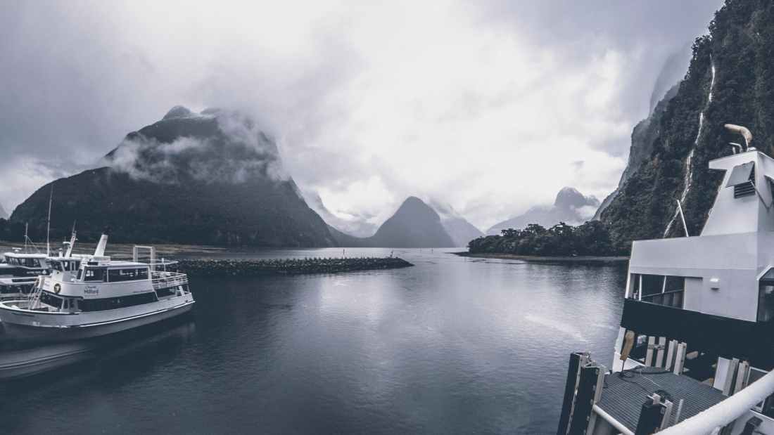 grayscale photo of yachts on body of water under cloudy sky