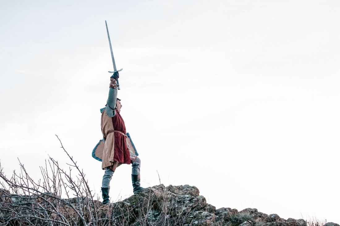 man in knight raising his sword