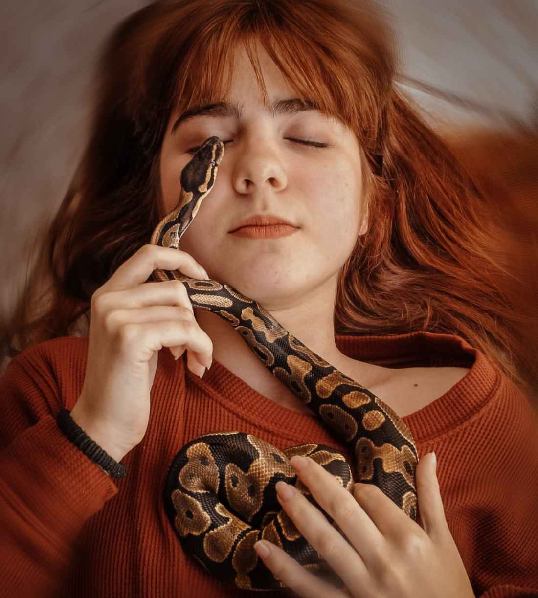 woman in knit sweater holding a snake